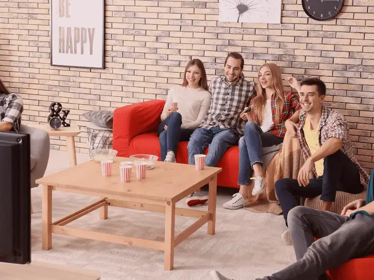 Família e amigos reunidos diante da TV na sala