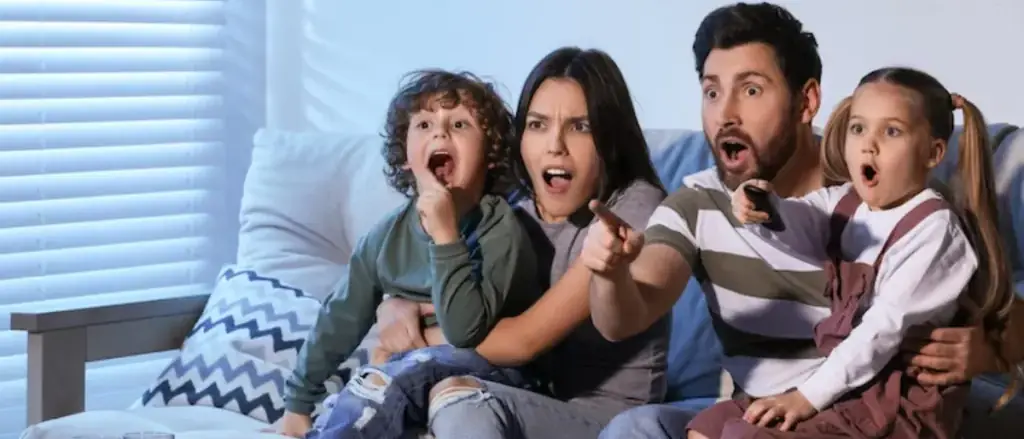 Família e amigos reunidos diante da TV na sala