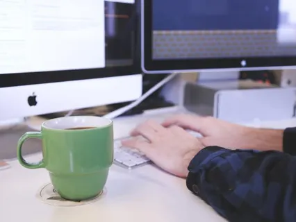 Mãos com computador e café no escritório