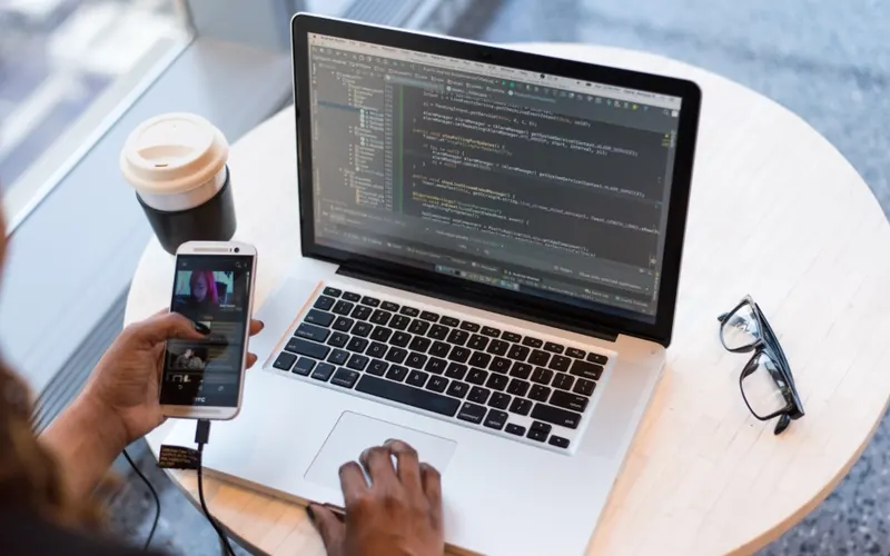 Mulher com celular e notebook no escritório